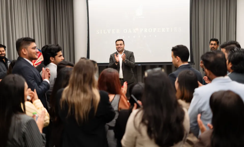 Guests applaud during a presentation, with Silver Oak Properties on the screen behind