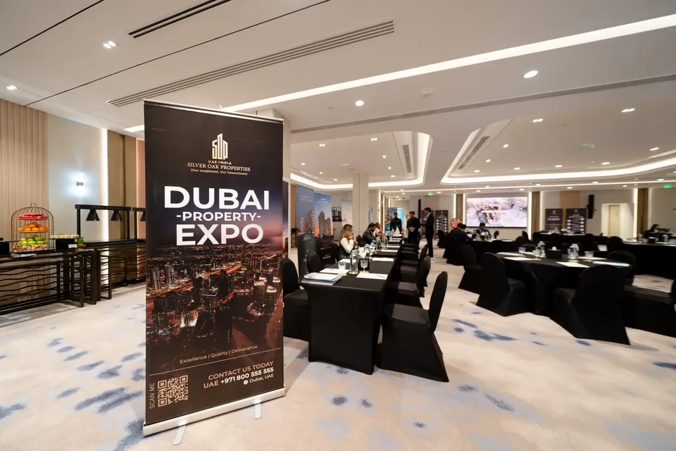 A Silver Oak Properties Dubai Property Expo banner stands in the foreground of the empty, ready conference room