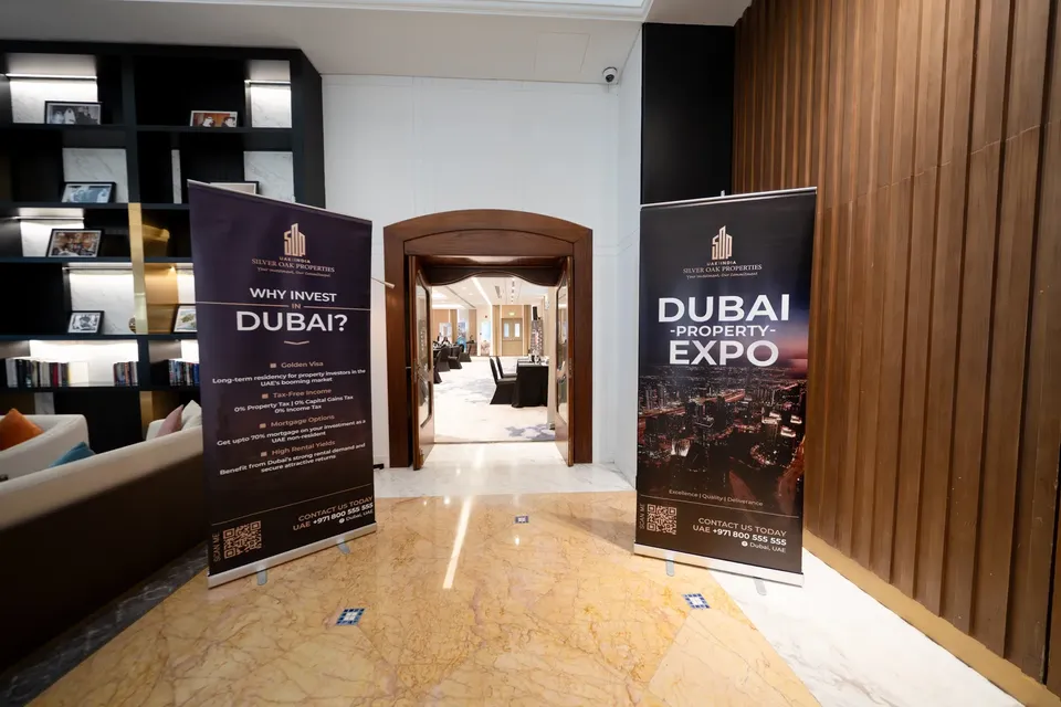 Two Silver Oak Properties roll-up banners stand in a marble-floored lobby, one reading Dubai Property Expo beside an open doorway