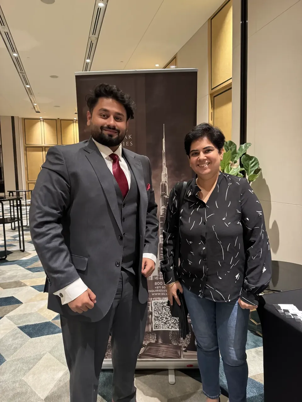 Two people pose beside a Silver Oak Properties banner showing the Burj Khalifa at the expo