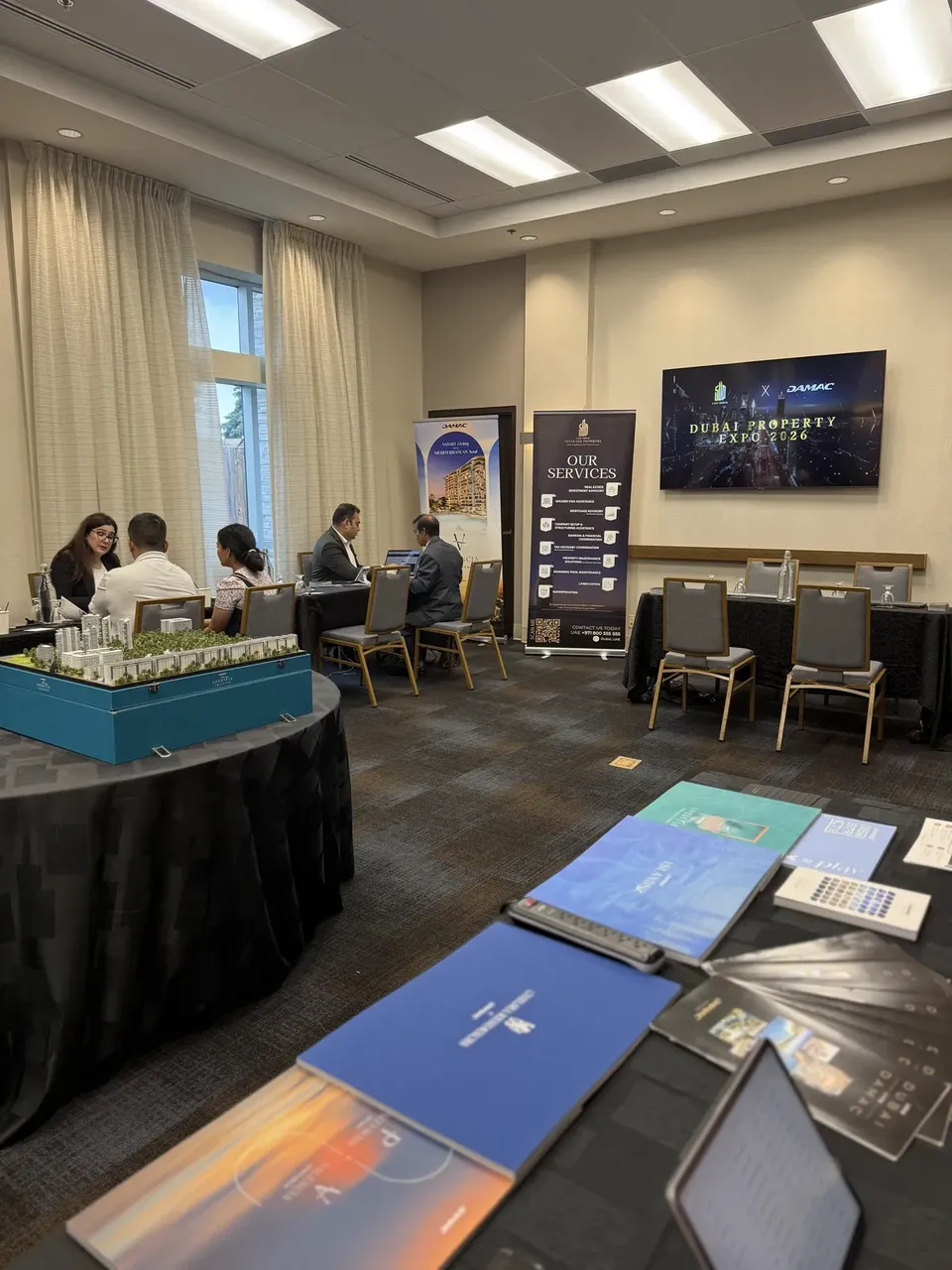 A consultation room at the expo, with advisers meeting a family at a table beneath a screen reading Dubai Property Expo 2026