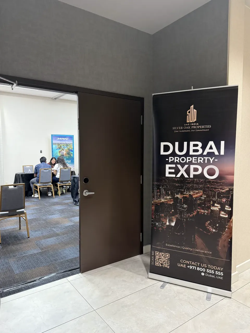 A Silver Oak Properties roll-up banner for the Dubai Property Expo stands beside an open doorway into a consultation room